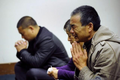 Familiares de los pasajeros del vuelo de Malaysia Airlines rezan, en un hotel de Pekín.-AFP / WANG ZHAO
