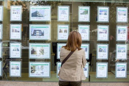Una mujer mira ofertas de compra y alquiler de viviendas.-EL PERIÓDICO