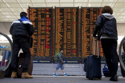 Dos viajeros comprueban la información de los vuelos en las pantallas del aeropuerto Charles de Gaulle, en Roissy (Francia).-Foto: EFE