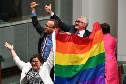 Tres diputados agitan la bandera arcoiris tras la aprobación de la ley.-MICK TSIKAS