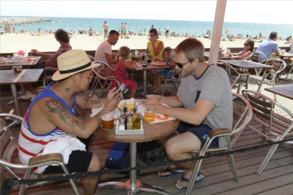 Dos turistas utilizan el móvil en una playa de Barcelona.-MÓNICA TUDELA