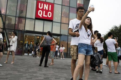 Una pareja de jóvenes se hacen un seli frente a la cadena de ropa Uniqlo, en Pekín.-Foto: AP