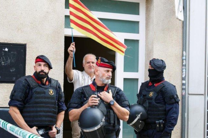 Un hombre con una ’senyera’, junto a unos agentes en la operación contra los CDR en Sabadell.-ANNA MAS