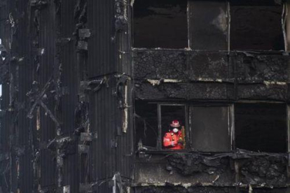 Un bombero inspecciona los restos de la Torre Grenfell, el edificio de apartamentos de 24 plantas en North Kensington, que se incendió el pasado sábado.-EFE