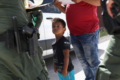 Un niño y sus padres, procedentes de Honduras, son retenidos por una patrulla policial cerca de la frontera de EEUU con México en Misión (Tejas), el 12 de junio pasado.-JOHN MOORE