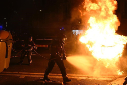 Bomberos apagan un contenedor en llamas en las protestas de los manifestantes contra un acto de Vox.-JORDI COTRINA