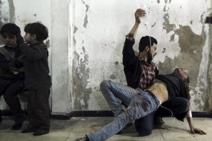 Un hombre da asistencia médica a un herido tras un ataque de las fuerzas del régimen al barrio de Duma, en Damasco.-REUTERS / MOHAMMED BADRA
