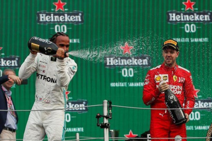 El británico Lewis Hamilton (i) de Mercedes celebra al ganar el Gran Premio de México de Fórmula Uno con el alemán Sebastian Vettel, segundo lugar, de Ferrari este domingo en el Autódromo Hermanos Rodríguez, en Ciudad de México.-EFE / José Méndez