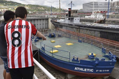 Dos jóvenes observan la gabarra con la que el Athletic Club celebró sus títulos en 1983 y 1984, que no saldrá del Museo Marítimo de Bilbao para festejar la Supercopa de España.-Foto: EFE / MIGUEL TOÑA