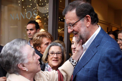 El presidente del Gobierno y candidato a la reelección por el PP, Mariano Rajoy, saluda a una mujer durante el recorrido que ha hecho hoy por las calles de Vigo, dentro de la campaña para las elecciones generales del 20D.-EFE