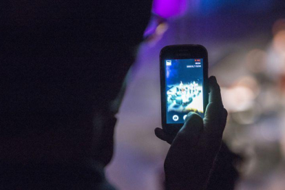 Un usuario utilizando su teléfono móvil durante la noche.-FERRAN SENDRA