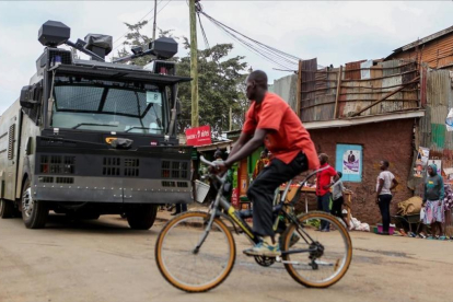 Un ciclista pasa por delante de un vehículo antidisturbios en las chabolas de Kibera, en Nairobi, el 7 de agosto.-REUTERS