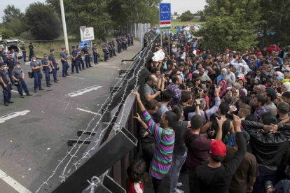 Refugiados sirios ante la valla fronteriza de Hungría.-MARKO DJURICA / REUTERS