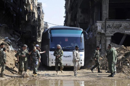 Militares del Ejército sirio supervisan un autobús que transporta combatientes vinculados a Al Qaeda durante una evacuación desde el campo de refugiados palestinos de Yarmuk, cerca de Damasc-SANA / AP
