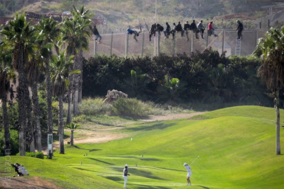 Dos jugadoras en un campo de golf, a pocos metros de la valla de la frontera de Melilla.-Foto: JOSÉ PALAZÓN