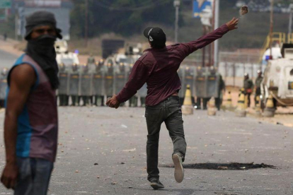 Un manifestante lanza una piedra contra policías venezolanos en la frontera con Brasil, este domingo. Un manifestante lanza una piedra contra policías venezolanos en la frontera con Brasil, este domingo.-REUTERS / BRUNO KELLY