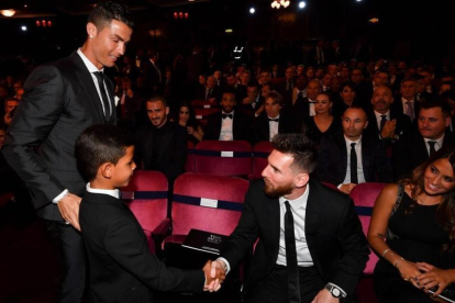 El hijo de Cristiano saluda a Messi en presencia de su padre y Antonella, en Londres.-AFP / BEN STANSALL