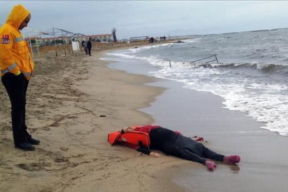 Un miembro de los equipos de rescate contempla el cuerpo de un inmigrante sobre la playa en Ayvalink (Turquía).-AP