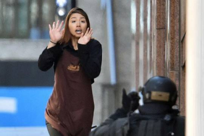 Una empleada del café sale corriendo del local, este lunes en Sídney.-Foto: AFP / SAEED KHAN