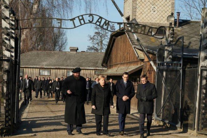 Angela Merkel cruza la puerta de entrada del campo de concentración de Auschwitz, bajo el siniestro cartel ’El trabajo os hará libres’.-AFP