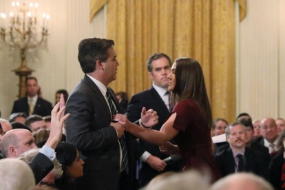 Trabajadores de la Casa Blanca intentan quitar el micrófono al periodista de la CNN.-REUTERS