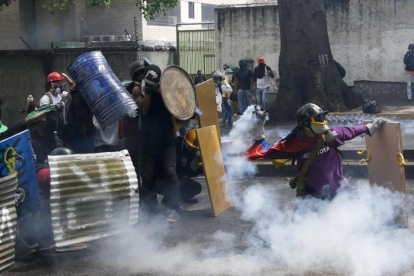 Manifestantes chocan con las fuerzas de seguridad chavistas durante una marcha en Caracas, el 1 de mayo.-AP / ARIANA CUBILLOS