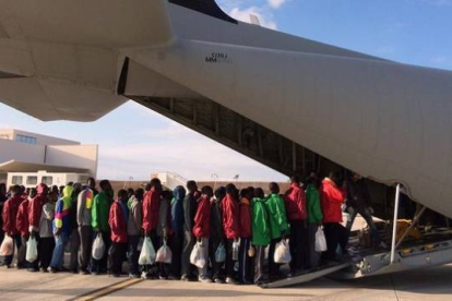 Inmigrantes subsaharianos hacen cola antes de subir a un avión militar que les trasladará a la península italiana, este lunes, en Lampedusa.-
