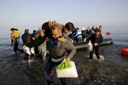 Un refugiado sirio llegado de Turquía carga con un niño en la isla griega de Kos.-Foto: REUTERS / YANNIS BEHRAKIS