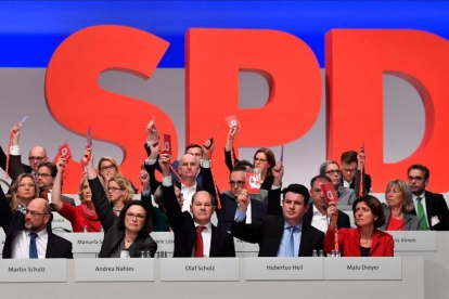 Miembros de la dirección del SPD votan, junto a los demás delegados, a favor de negociar con Merkel.-/ AFP / JOHN MACDOUGALL