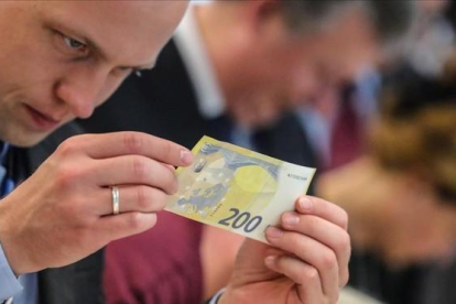 Un periodista inspecciona un nuevo billete de 200 euros, presentados este lunes.-ARMANDO BABANI