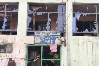 Un hombre habla por su teléfono móvil desde la entrada a su tienda dañada por un atentado cerca del Ministerio de Defensa en Kabul, Afganistán.-JAWAD JALALI