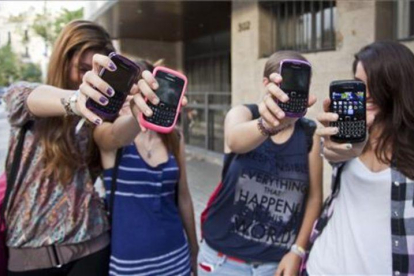 Unas adolescentes muestran sus teléfonos móviles a la puerta de su instituto en Barcelona.-
