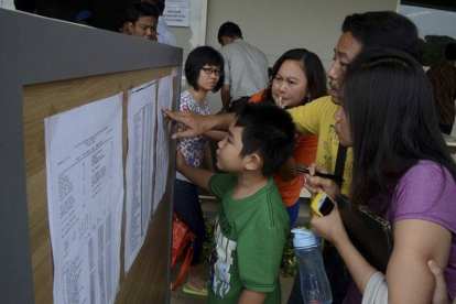 Familiares de los pasajeros del vuelo desaparecido miran una lista en el aeropuerto de Surabaya, este domingo.-Foto: ANTARA FOTO / REUTERS