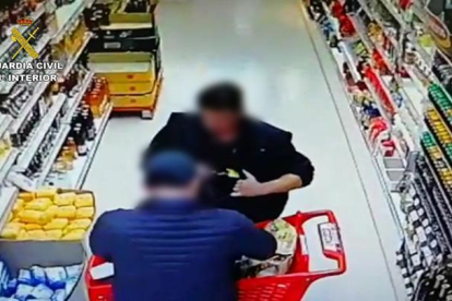 El detenido escondiendo bajo su ropa una de las botellas sustraídas en el supermercado de El Burgo de Osma.-HDS