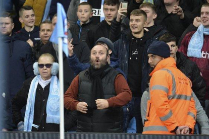 Un aficionado del Manchester City hace gestos racistas a los jugadores del United.-EFE / PETER POWELL