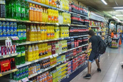Un joven, ante la estantería de refrescos de cola, en un supermercado-/ FERRAN SENDRA
