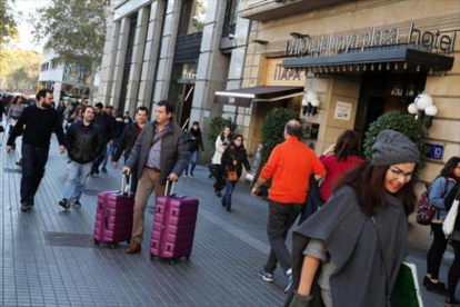 Viandantes cerca de un hotel en la plaza de Cataluña de Barcelona.-RICARD CUGAT