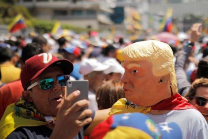 Manifestantes a favor de Maduro con caretas de Donald Trump, este sábado en Caracas.-REUTERS / CARLOS BARRIA