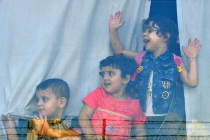 Niños refugiados sirios miran a través de la ventana de un autobús antes de abandonar Beirut este domingo de regreso a sus hogares en Siria.-EFE / WAEL HAMZEH