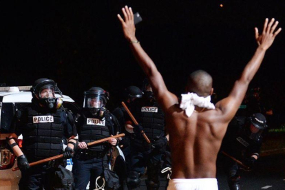 Un joven levanta los brazos ante la policía en Charlotte.-JEFF SINER / AP