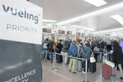 Colas de pasajeros en los mostradores de facturación de Vueling en El Prat .-Foto: DANNY CAMINAL