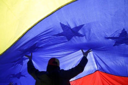 Una mujer sujeta una gran bandera de Venezuela.-ANDREA COMAS (AP)