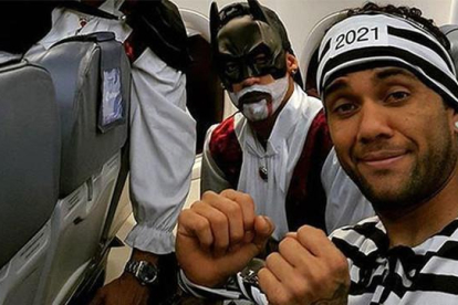 Alves, vestido de presidiario, junto a Suárez, con un disfraz de Batman, en el avión de regreso a Barcelona.-TWITTER