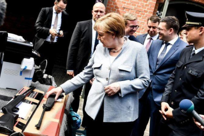 La cancillera alemana Angela Merkel observa armas de fuego durante su visita al Departamento Federal de la Policía en Pasewalk.-EFE / FILIP SINGER