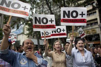 Manifestantes contrarios a Maduro sostienen pancartas en las que reclaman que se acabe la dictadura en Venezuela.-ARIANA CUBILLOS (AP)