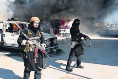 Dos miembros del ISIL, el pasado mes de enero, frente a un coche policial en llamas en Irak.-Foto: AP