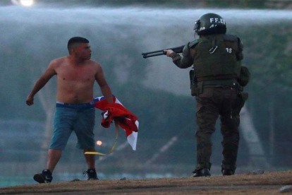 Un polícia en Chile apunta con su arma a un manifestante.-REUTERS