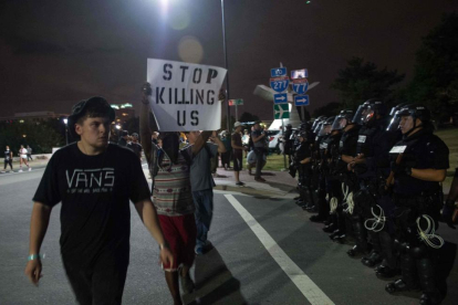 Manifestantes pasean con pancartas ante el cordón policial, esta madrugada en Charlotte.-AFP / NICHOLAS KAMM