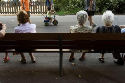 Un grupo de ancianos descansan en un banco en un parque.-EL PERIÓDICO