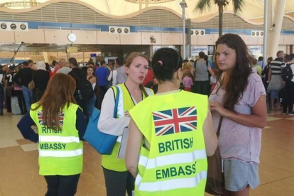 Una turista habla con personal de la Embajada británica en Egipto mientras otros hacen cola para el 'check in', en el aeropuerto de Sharm al Sheij, este viernes.-AP / THOMAS HARTWELL